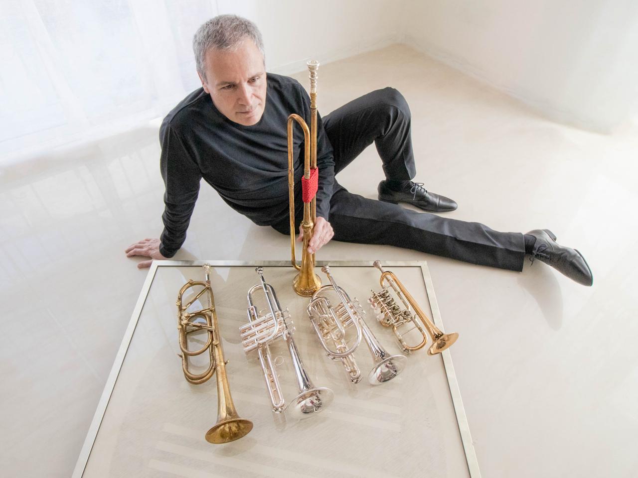 Gabriele Cassone seated on the floor beside six trumpets